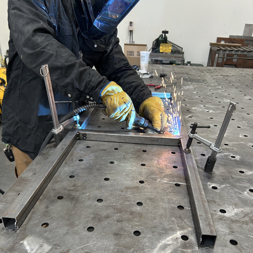 DIY welding cart frame clamped in place as welding sparks fly during fabrication